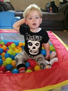 My Rocking Kids - Little boy sitting in a ball pall in black t-shirt with misfits and a skull in white