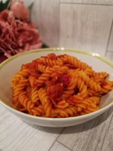 Pasta Amatriciana - A bowl of tomato sauce covered pasta with bits of bacon scattered throughout