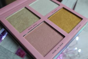 January Makeup Favourites - A pink square package with 4 different pans inside. A pale pink with "made you blush" underneath, above that is a pale gold with "dollar dollar" written underneath. To the right is a white pan but the writing under is blurred and below that is a bright gold with "Gold dust underneath"