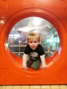 Soft Play Mum Guilt - Toddler climbing out of an orange plastic hole