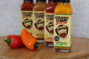 Screaming Chimp - 4 sauce bottles lined up behind each other on a wooden board