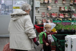 Loneliness in the elderly - A small boy in a dark red top and an elderly lady in a cream coat following him. 