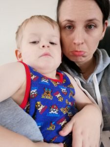One Perfect Week - Sulking toddler in a blue and red vest with mummy behind pulling a sulky face too.