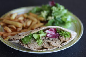 Healthy Doner Kebab - Sliced meat and lettuce leaves inside a pitta bread, on a plate with chips and more lettuce.