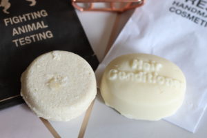 Lush Hair Care bars - two creamy coloured bars laying on their paper packaging