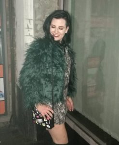 Remove negativity from your life - Carly out out dressed in a furry green jacket and leopard print dress with a look on her face that says "screw you anxiety"