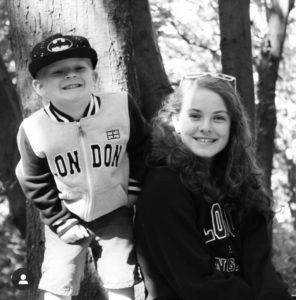 Things to do with the kids in January - A black and white picture of Carly's 2 children in the woods smilling at the camera