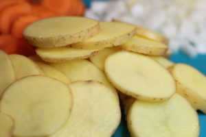 Minces Beef Hotpot - thinly sliced potatoes in front of diced onion and sliced carrot