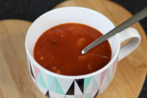 Mexican Chilli Bean Soup - A mug style bowl with geometric shapes on it holding the soup and a silver spoon resting in the soup