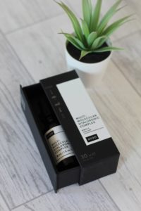 DECIEM - A small black box with a white label that's half open revealing a dark bottle with a white label on it