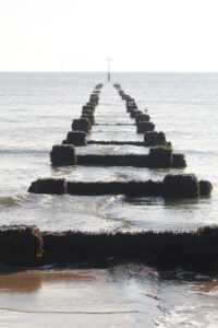 Sea Safety - a wooden groyne going out to sea. The water looks flat and grey