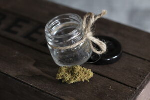 Another strain of Herbaleyes flowers on a dark wood crate with the open jar behind it.