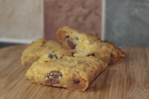 A close up of the finished Mini Egg Cookie bar, sliced and sitting on a chopping board.