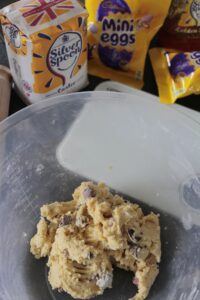 The Mini Egg Cookie Bar dough in a mixing bowl with some of the ingredients behind